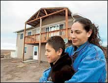 A TOWN REBORN: Marla Herman and her son Trinityat sit outside a home she built on the Pine Ridge Reservation in Allen, S.D.