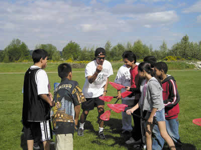Angelo Baca teaches lacrosse to a group of children from Chief Leschi School as part of the 21st Century Afterschool program’s Inter-Tribal games. (Photo courtesy Betsy Fradd)