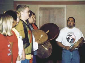 Performers –—The Tribe’s Language Specialist Tony Johnson leads Tribal youth in a song. The children sang a favorite stick game song for the 70 or so teachers.