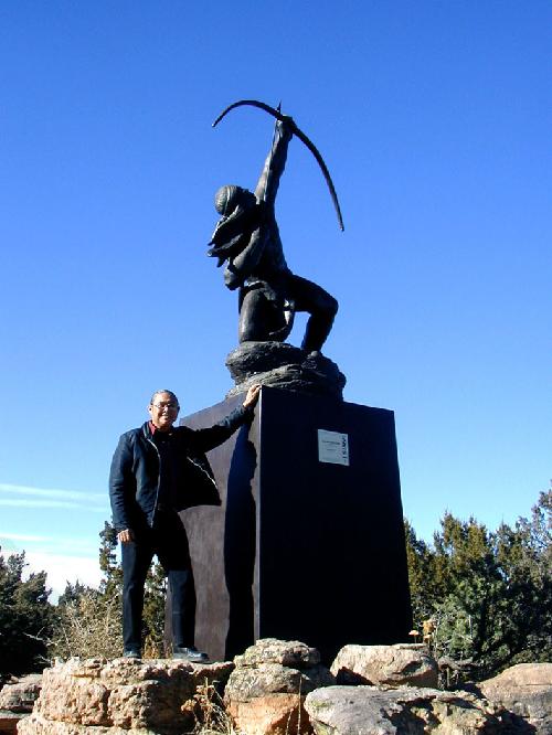 Phillip M. Haozous, standing next to the Sacred Rain Arrow statue